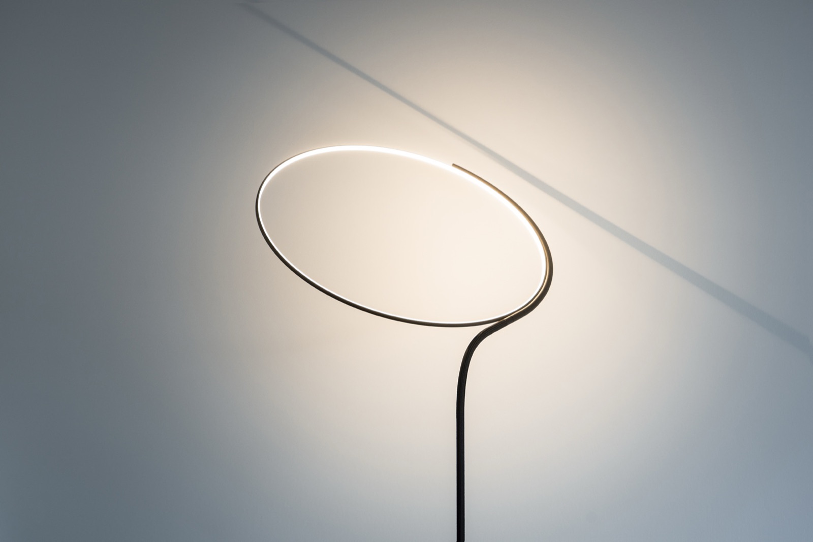 Poise floor lamp arching over a lounge chair